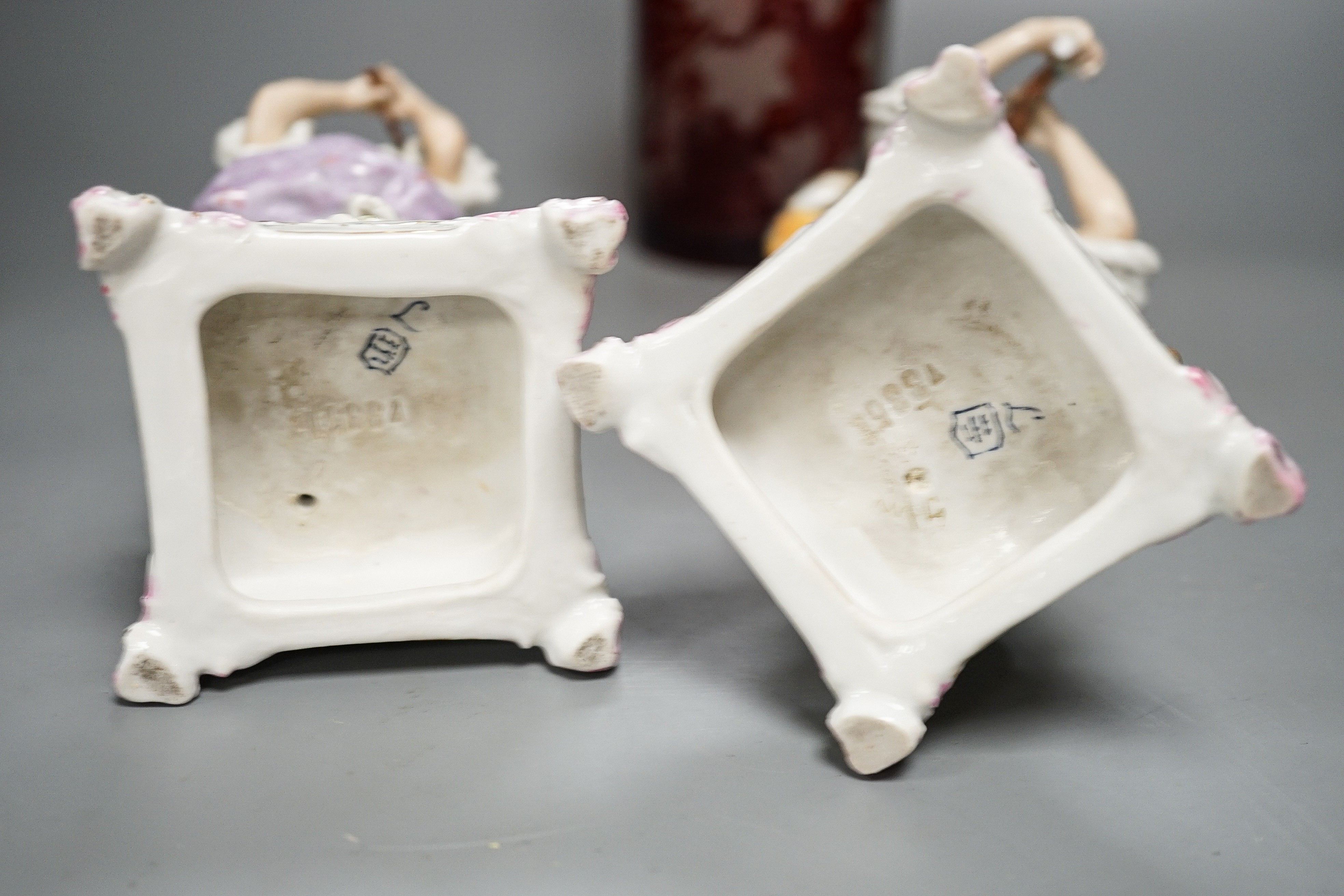 A late 19th century Bohemian wheel engraved ruby glass decanter and a pair of continental porcelain figures, decanter 37 cms high, including stopper.